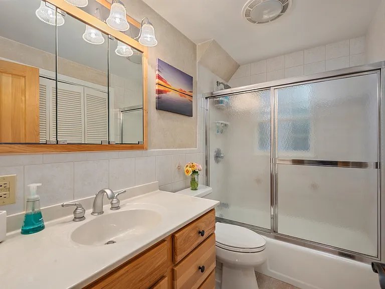 Bathroom with natural wood vanity and triple-mirror cabinet at The Brookhurst Lake House