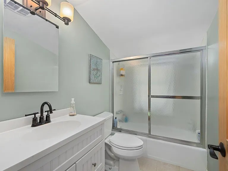 Sage-green bathroom with white vanity at The Brookhurst Lake House