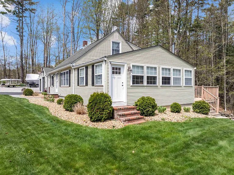 Side arrival view of the cottage-style exterior with lawn and landscaping